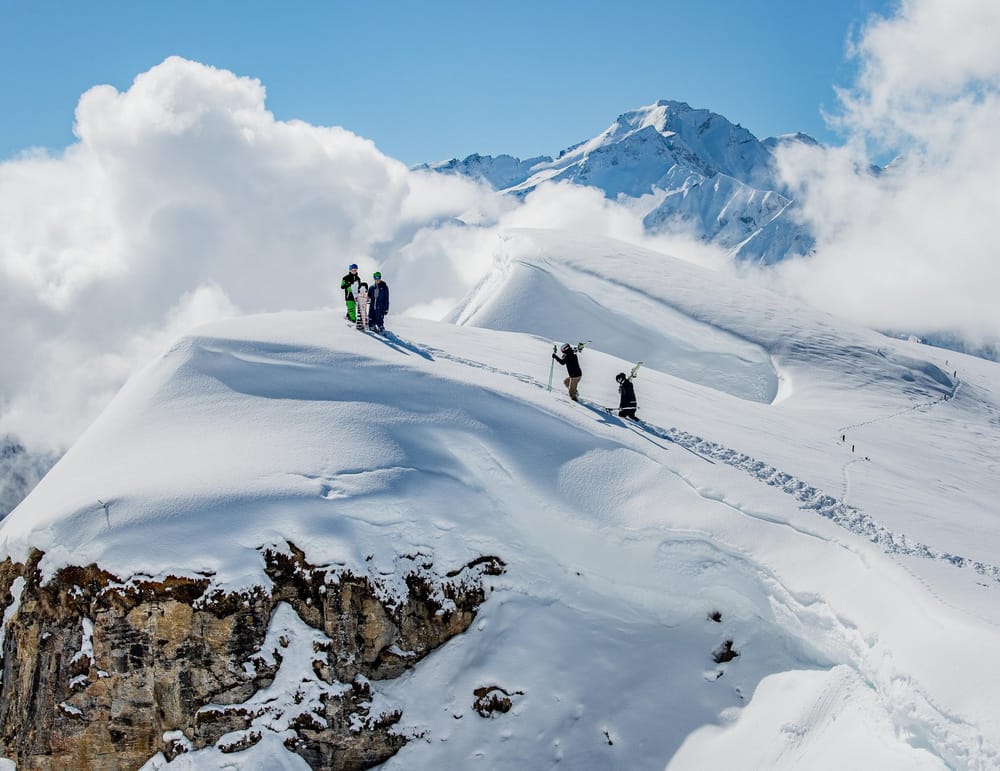 Skitourengänger im Schnee auf Berg vor blauem Himmel in der Surselva