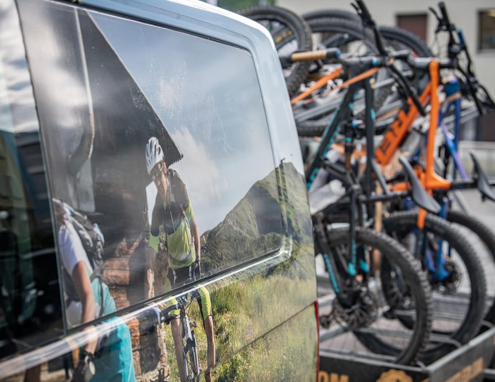 Schwarzer Bus mit Anhänger und viele Bikes drauf