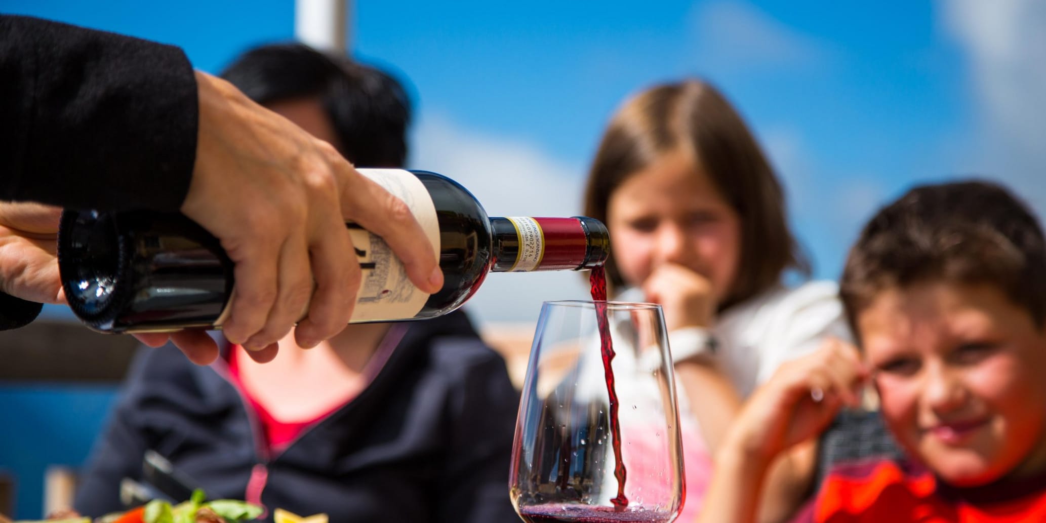 Wein wird eingeschenkt im Hintergrund Mädchen und Junge