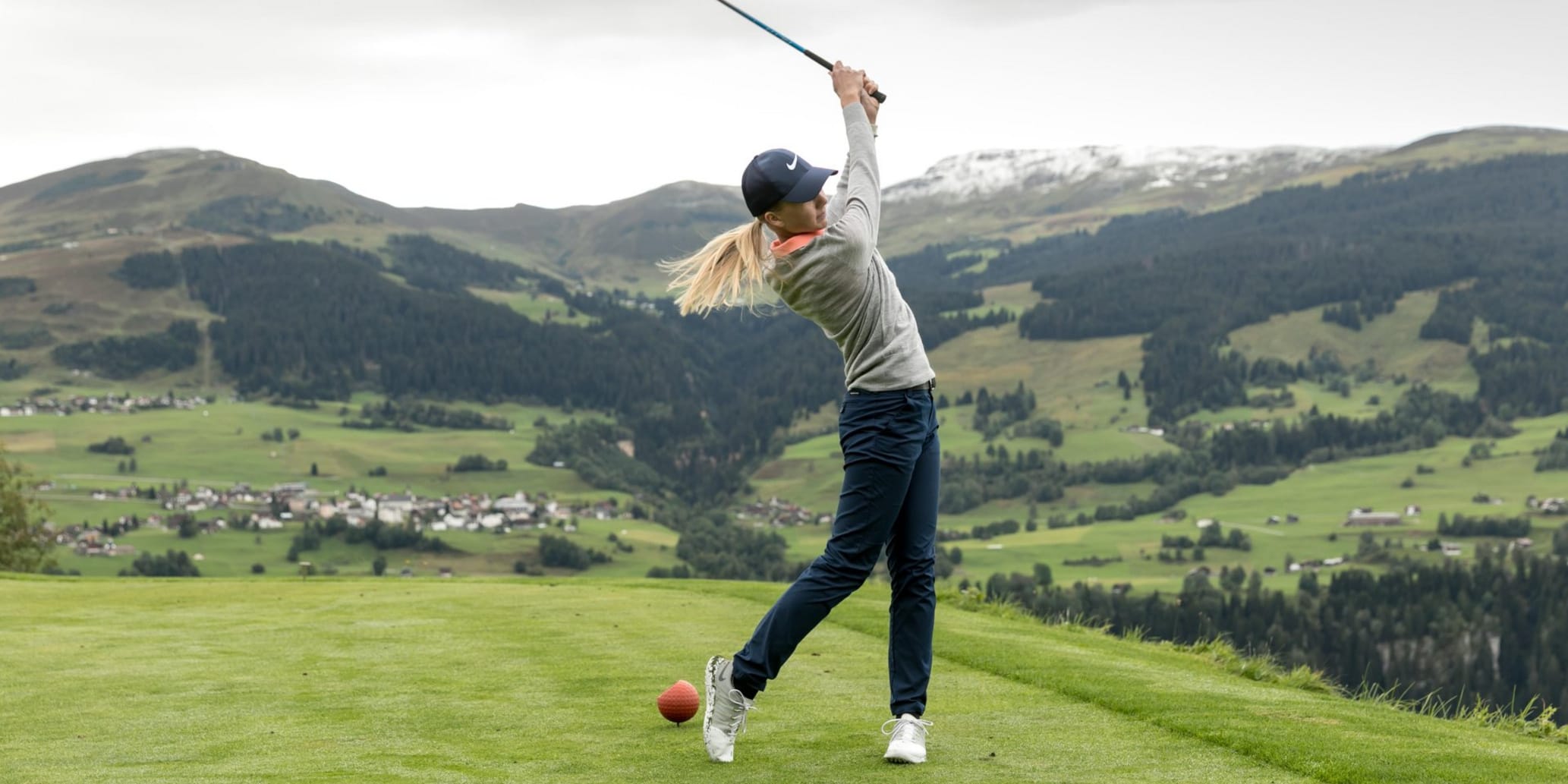 Frau beim Abschlag auf Golfplatz in der Surselva
