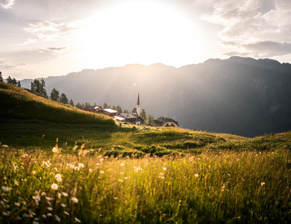 Blumenwiese Bergdorf im Hintergrund bei Sonnenaufgang