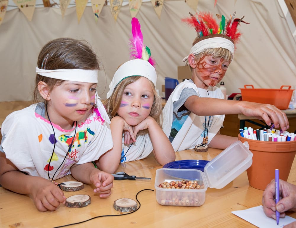 Kinder basteln am Tisch für Indianerprojekt im Tippi