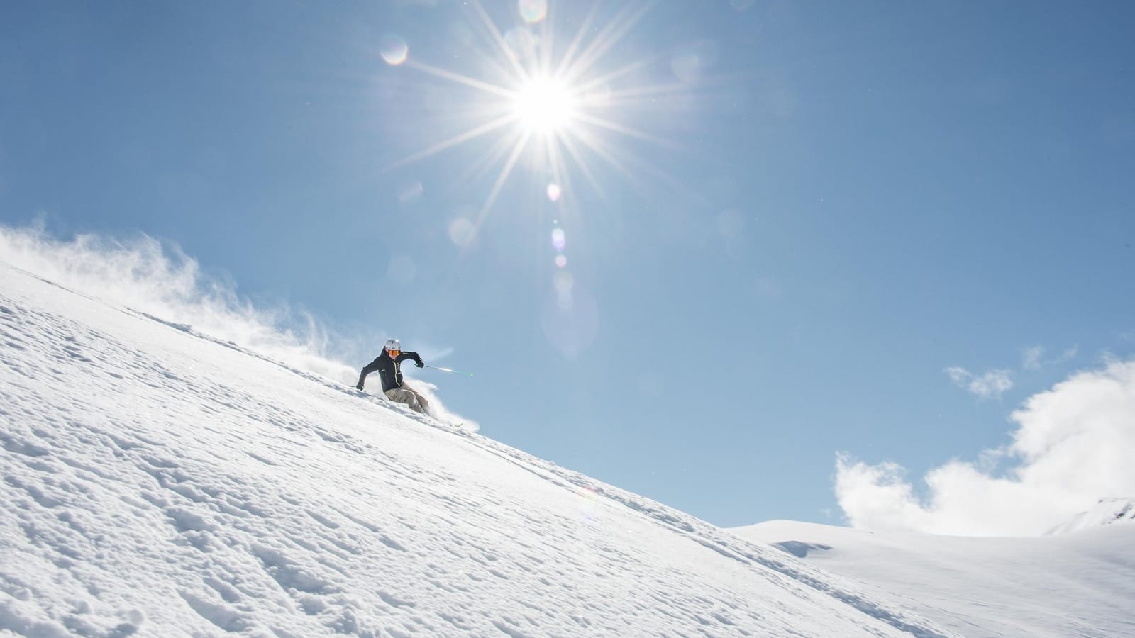 Skifahrer auf Abfahrt bei blauem Himmel und Sonnenschein