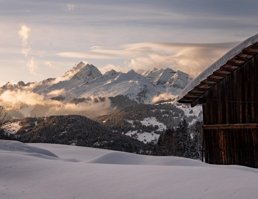 Maiensäss rechts im Hintergrund Berglandschaft am späteren Nachmittag