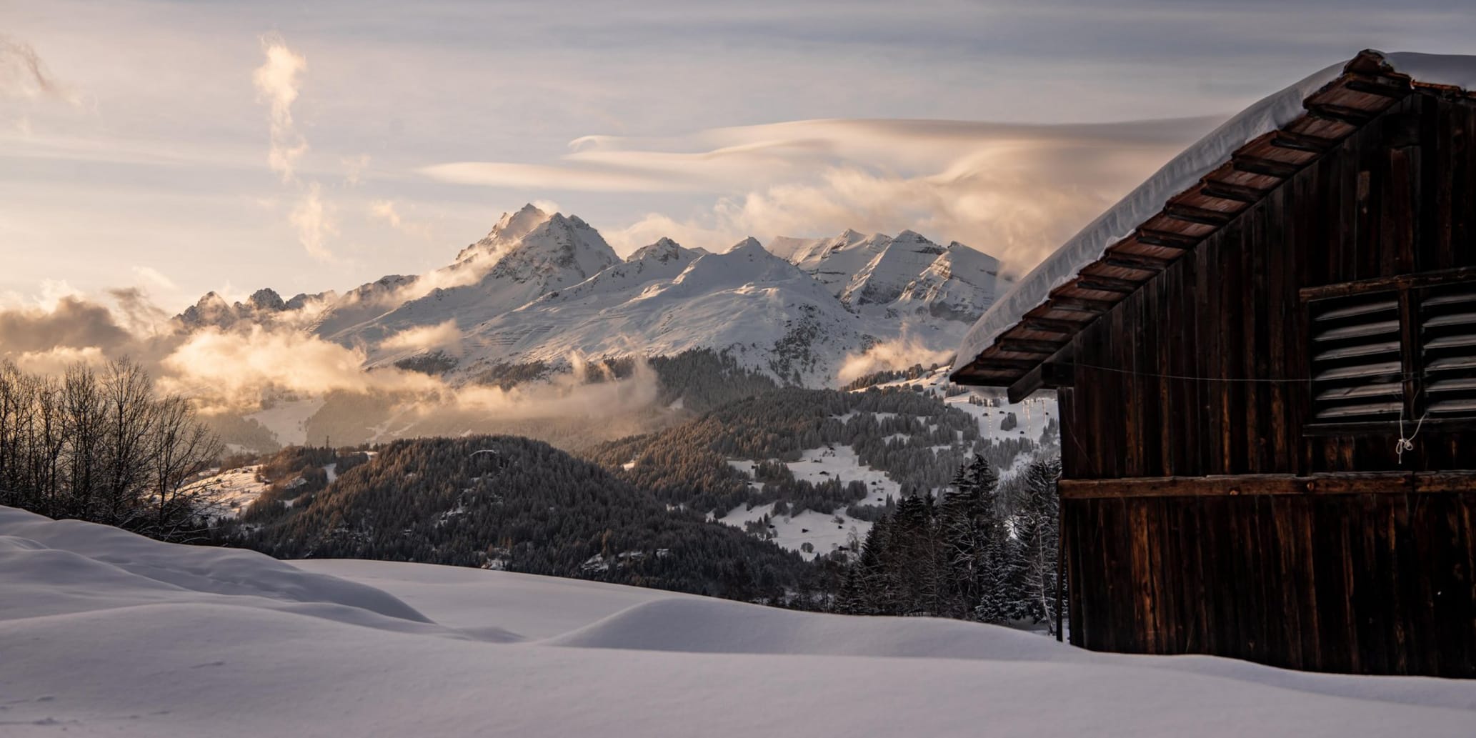 Maiensäss rechts im Hintergrund Berglandschaft am späteren Nachmittag